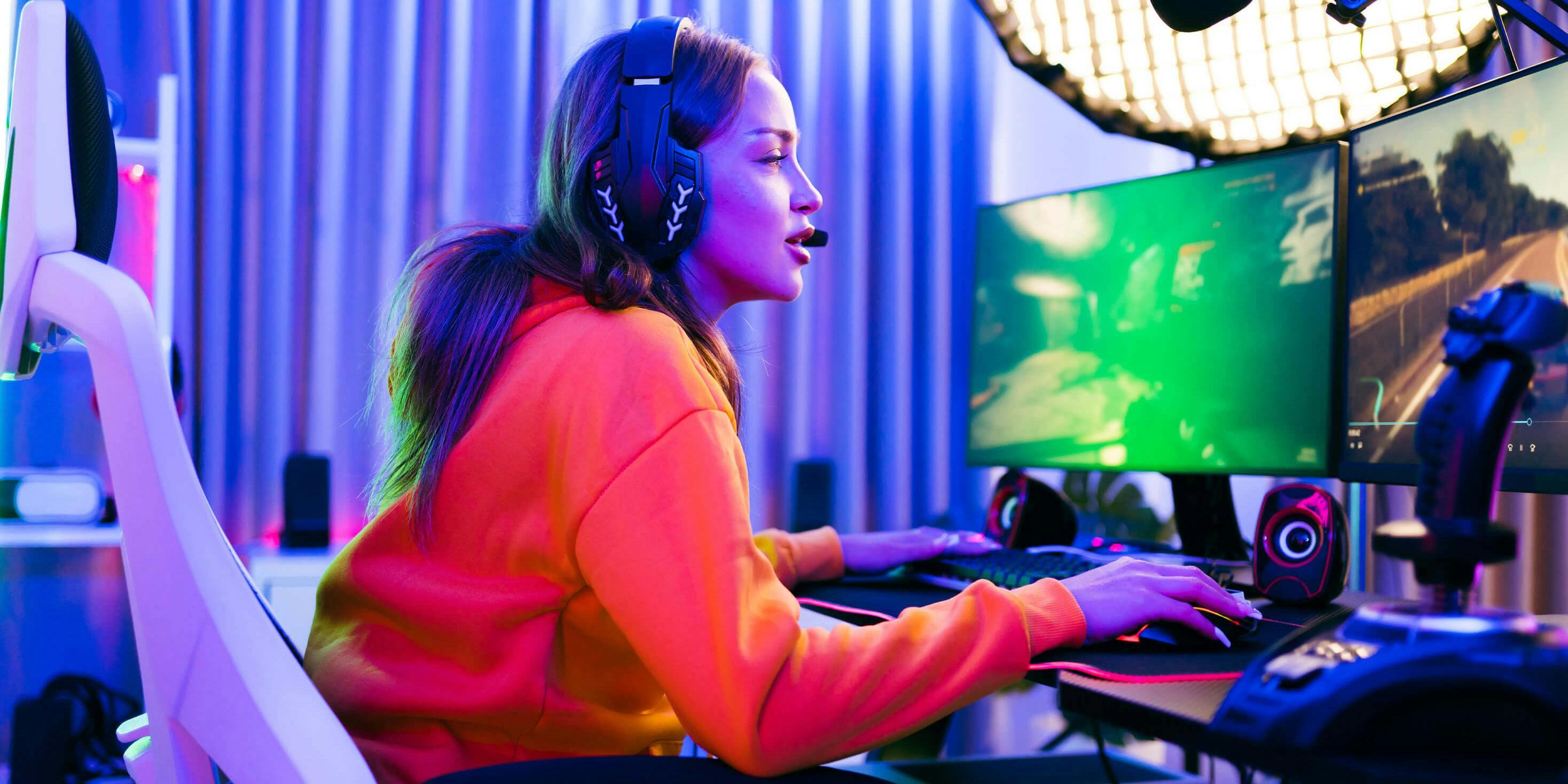 A person in a bright orange hoodie sits in a gaming chair and livestreams a video game to their viewers.