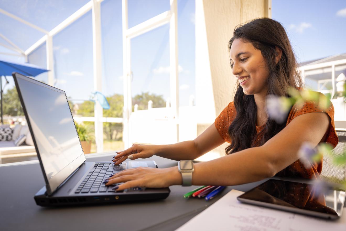 A female student enjoying working outside on her laptop.